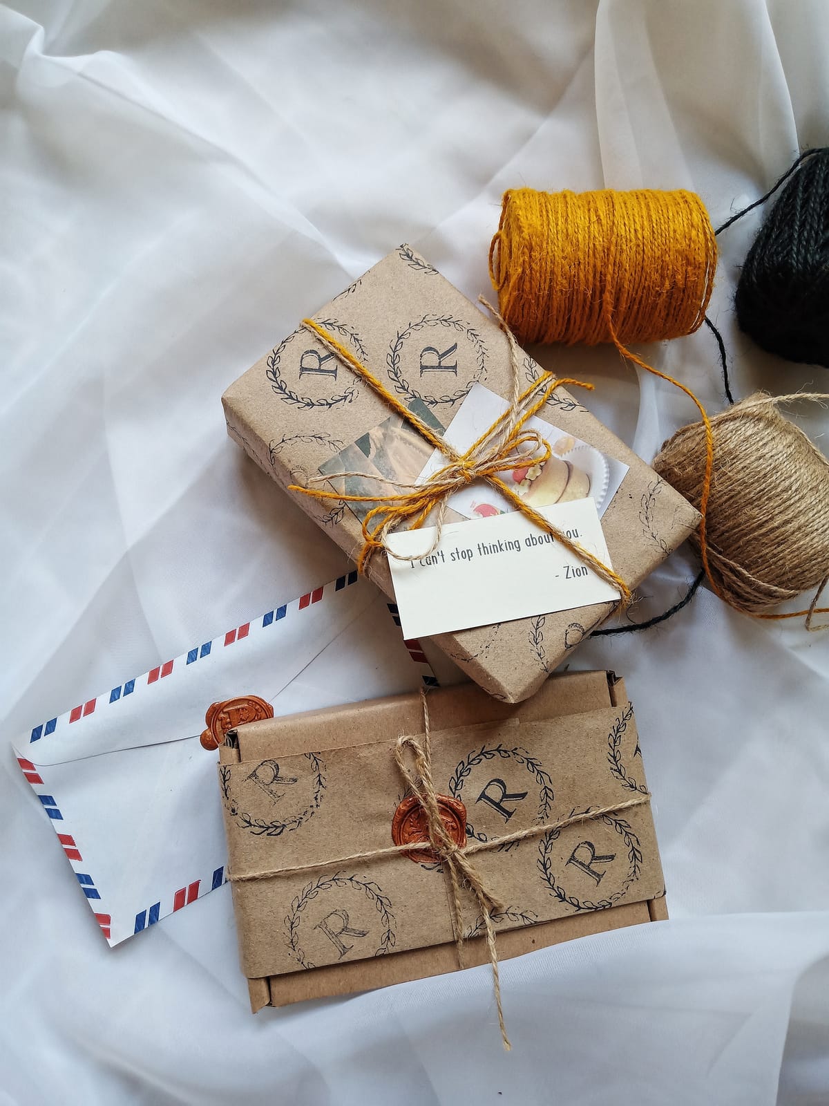 A kraft-paper parcel hand-stamped with the laurel-R monogram, tied with jute and mustard twine and closed with a wax seal